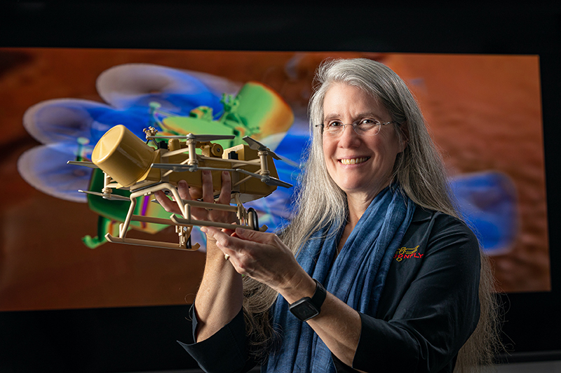 Elizabeth “Zibi” Turtle, recipient of the Division for Planetary Science’s Claudia J. Alexander Prize, holds a scale model of the Dragonfly spacecraft.  Credit: Johns Hopkins APL/Ed Whitman
