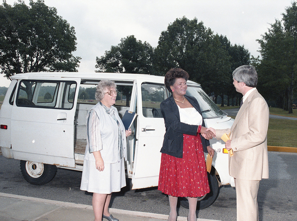 Pete Newman, right, head of transportation and traffic at APL, presents keys to the van (background) to Dottie Moore, Executive Director of the Howard County Community Action Council