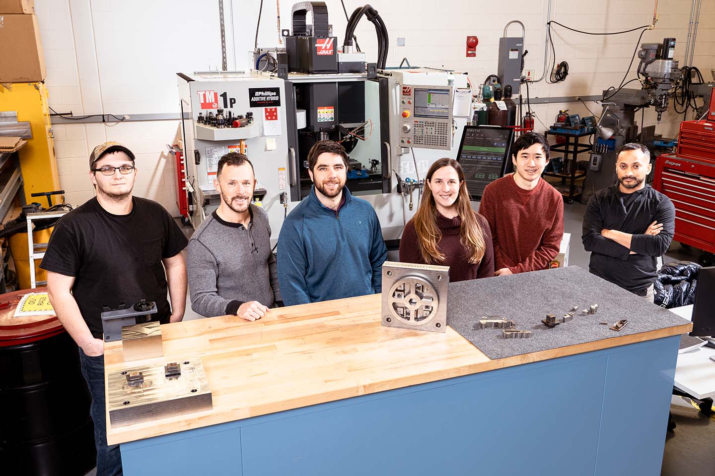 From left: Hunter Turco, Jason Reese, Ben Miller, Sarah Bostwick, Alan Huang and Deepu David stand in front of a 3D printer system
