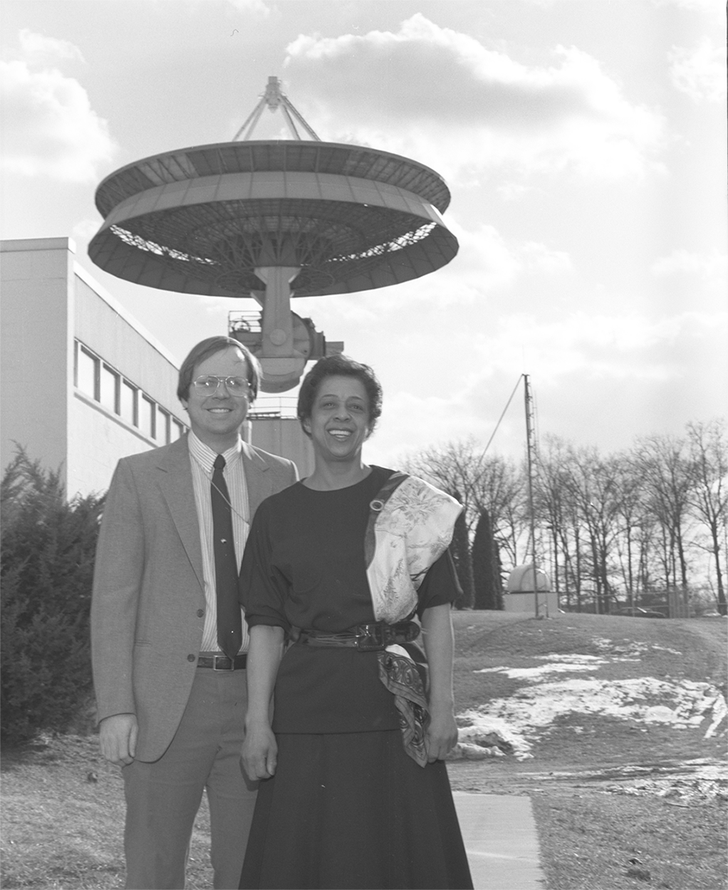 3.	Dobson and David Porter pose in front of the Injection Station and the 60-foot antenna dish on APL’s Main Campus in Laurel, Maryland