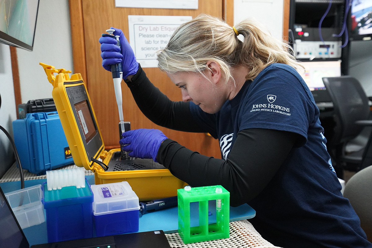 Hayley DeHart, a genomics research scientist at APL, loads water samples into a sequencer while on board a ship during the team’s trip to Monterey Bay.