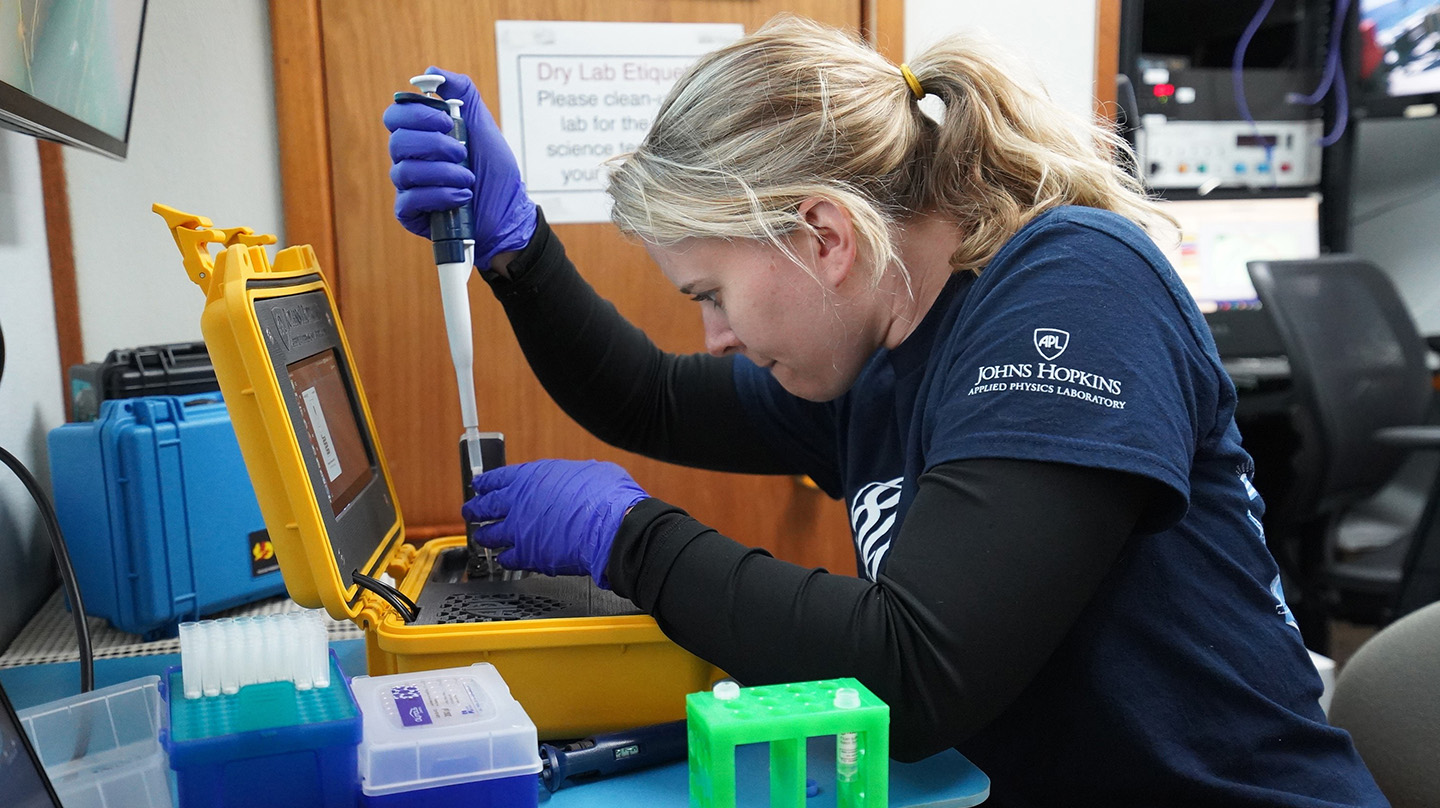 Hayley DeHart, a genomics research scientist at APL, loads water samples into a sequencer while on board a ship during the team’s trip to Monterey Bay.