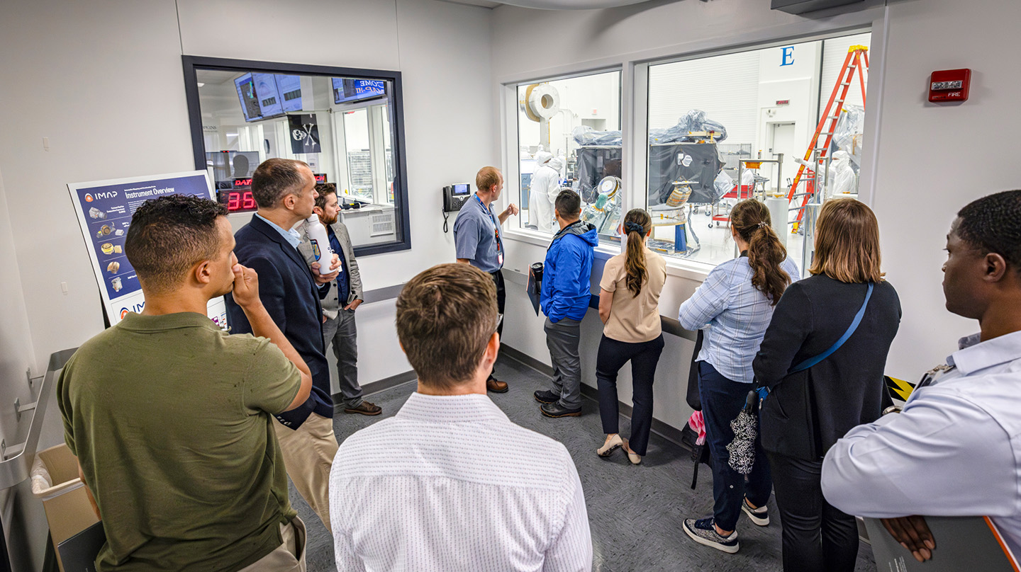 During their tour of APL’s campus, students in the U.S. Space Force’s professional military education program had a chance to view NASA’s Interstellar Mapping and Acceleration Probe (IMAP) spacecraft, currently being built and tested in one of APL’s cleanrooms. (Credit: Johns Hopkins APL/Ed Whitman)