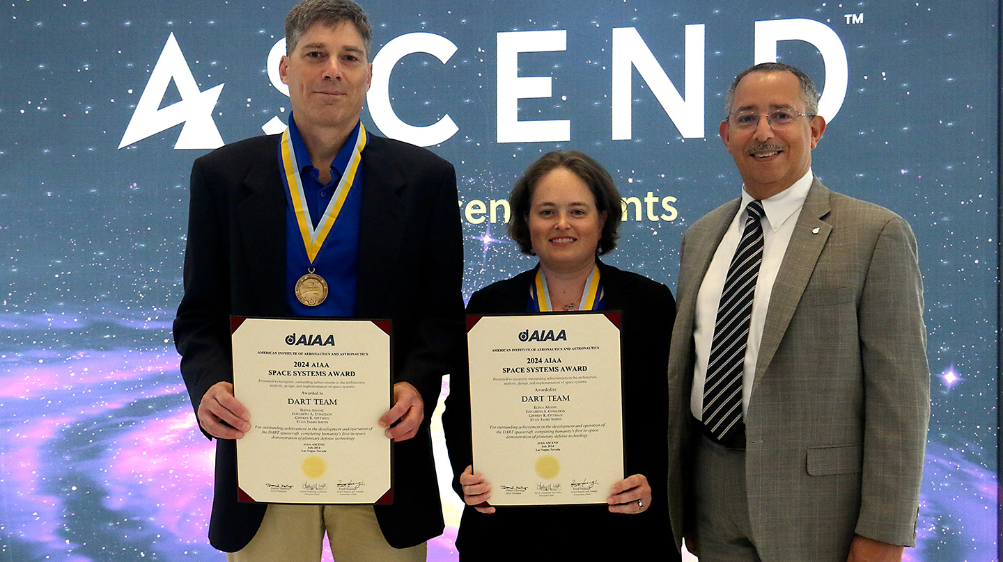 Geffrey Ottman (left) and Betsy Congdon (center) accept the 2024 AIAA Space Systems Award on behalf of the DART team