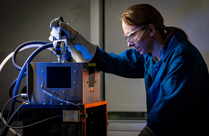 An APL staff member melts an alloy of zirconium and titanium in the arc melter. (Credit: Johns Hopkins APL/Ed Whitman)