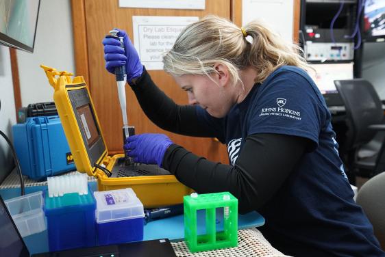 Hayley DeHart, a genomics research scientist at APL, loads water samples into a sequencer while on board a ship during the team’s trip to Monterey Bay.